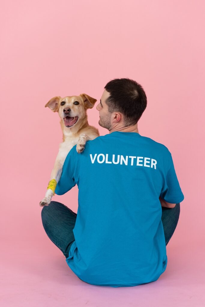 Man sitting with dog in Volunteer T-Shirt